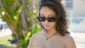 Young beautiful hispanic woman tourist looking down with serious expression at park Royalty Free Stock Photo