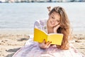 Young beautiful hispanic woman tourist reading book lying on sand at beach Royalty Free Stock Photo