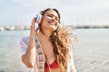 Young beautiful hispanic woman tourist wearing bikini listening to music at beach Royalty Free Stock Photo