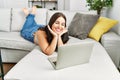 Young beautiful hispanic woman using laptop lying on sofa at home Royalty Free Stock Photo