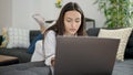 Young beautiful hispanic woman using laptop lying on sofa at home Royalty Free Stock Photo