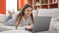 Young beautiful hispanic woman using laptop lying on sofa at home Royalty Free Stock Photo