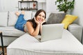 Young beautiful hispanic woman using laptop lying on sofa at home Royalty Free Stock Photo