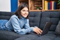 Young beautiful hispanic woman using laptop lying on sofa at home Royalty Free Stock Photo