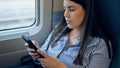 Young beautiful hispanic woman using smartphone sitting inside train wagon Royalty Free Stock Photo