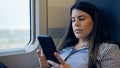 Young beautiful hispanic woman using smartphone sitting inside train wagon Royalty Free Stock Photo