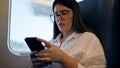 Young beautiful hispanic woman using smartphone sitting inside train wagon Royalty Free Stock Photo