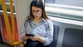 Young beautiful hispanic woman using smartphone sitting on the subway Royalty Free Stock Photo