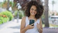 Young beautiful hispanic woman using smartphone smiling at park Royalty Free Stock Photo