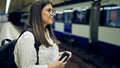 Young beautiful hispanic woman waiting for the subway using smartphone in subway station of Madrid Royalty Free Stock Photo