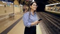 Young beautiful hispanic woman waiting for the subway using smartphone in subway station of Madrid Royalty Free Stock Photo