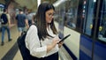 Young beautiful hispanic woman waiting for the subway using smartphone in subway station of Madrid Royalty Free Stock Photo