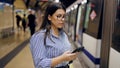 Young beautiful hispanic woman waiting for the subway using smartphone in subway station of Madrid Royalty Free Stock Photo