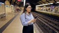 Young beautiful hispanic woman waiting for the subway using smartphone in subway station of Madrid Royalty Free Stock Photo