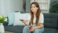 Young beautiful hispanic woman watching movie drinking tea at home Royalty Free Stock Photo