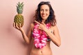 Young beautiful hispanic woman wearing bikini holding pineapple smiling happy pointing with hand and finger Royalty Free Stock Photo