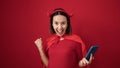 Young beautiful hispanic woman wearing devil costume using smartphone over isolated red background Royalty Free Stock Photo