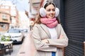 Young beautiful hispanic woman wearing scarf and earmuff standing with arms crossed gesture at street Royalty Free Stock Photo