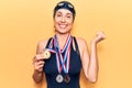 Young beautiful hispanic woman wearing swimmer swimwear and winner medals screaming proud, celebrating victory and success very Royalty Free Stock Photo