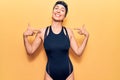 Young beautiful hispanic woman wearing swimwear and swimmer glasses looking confident with smile on face, pointing oneself with Royalty Free Stock Photo