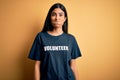 Young beautiful hispanic woman wearing volunteer t-shirt as social charity moral puffing cheeks with funny face