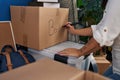 Young beautiful hispanic woman writing book word on package at new home Royalty Free Stock Photo