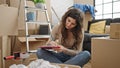 Young beautiful hispanic woman writing on document sitting on floor at new home Royalty Free Stock Photo