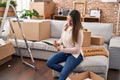 Young beautiful hispanic woman writing on notebook sitting on sofa at new home Royalty Free Stock Photo