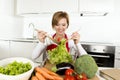 Young beautiful home cook woman at modern kitchen preparing vegetable salad bowl smiling happy Royalty Free Stock Photo