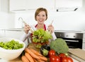 Young beautiful home cook woman at modern kitchen preparing vegetable salad bowl smiling happy Royalty Free Stock Photo