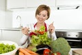 Young beautiful home cook woman at modern kitchen preparing vegetable salad bowl smiling happy Royalty Free Stock Photo