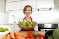 Young beautiful home cook woman at modern kitchen preparing vegetable salad bowl smiling happy Royalty Free Stock Photo