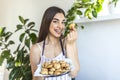 Young beautiful housewife holding freshly baked cookies on a tray in the kitchen Royalty Free Stock Photo