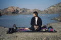 Young beautiful indian girl reading a book while leaning down on the ground wearing a black coat. Concept of having picnic in a Royalty Free Stock Photo