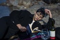 Young beautiful indian girl reading a book while leaning down on the ground wearing a black coat. Concept of having picnic in a Royalty Free Stock Photo