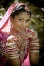 Young beautiful Indian Hindu bride sitting in garden outdoors