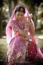 Young beautiful Indian Hindu bride sitting under tree with painted hands raised Royalty Free Stock Photo