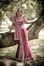Young beautiful Indian Hindu bride standing under tree