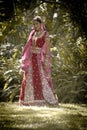 Young beautiful Indian Hindu bride standing under tree