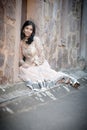 Young beautiful Indian Woman sitting against stone wall outdoors