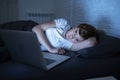 Young beautiful internet addicted sleepless and tired woman working on laptop in bed late at night Royalty Free Stock Photo