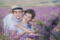 Young beautiful lady mother with lovely daughter walking on the lavender field on a weekend day in wonderful dresses and hats. Royalty Free Stock Photo