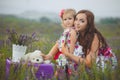 Young beautiful lady mother with lovely daughter walking on the lavender field on a weekend day in wonderful dresses and hats. Royalty Free Stock Photo