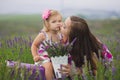 Young beautiful lady mother with lovely daughter walking on the lavender field on a weekend day in wonderful dresses and hats. Royalty Free Stock Photo