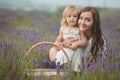 Young beautiful lady mother with lovely daughter walking on the lavender field on a weekend day in wonderful dresses and hats. Royalty Free Stock Photo