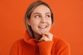 Young beautiful lady in orange sweater touching her chin