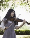 Young beautiful lady playing violin with happy feeling,in a park Royalty Free Stock Photo