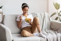 Young and beautiful lady sitting on couch, eating salad Royalty Free Stock Photo