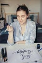 Young beautiful lady sitting at white desk and think about calligraphy Royalty Free Stock Photo