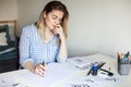 Young beautiful lady sitting at white desk and think about calligraphy Royalty Free Stock Photo